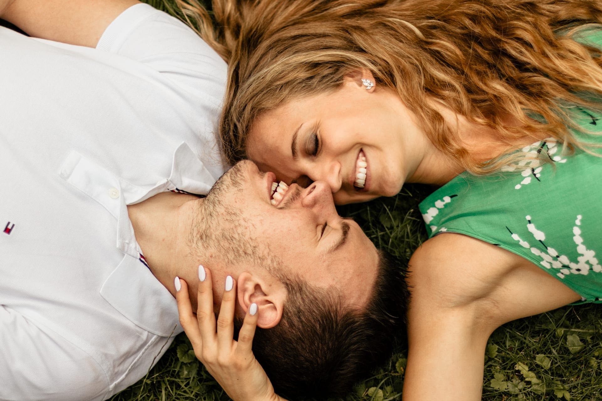 Détail vue plongée couple allongé dans l'herbe baiser complice — séance couple nature