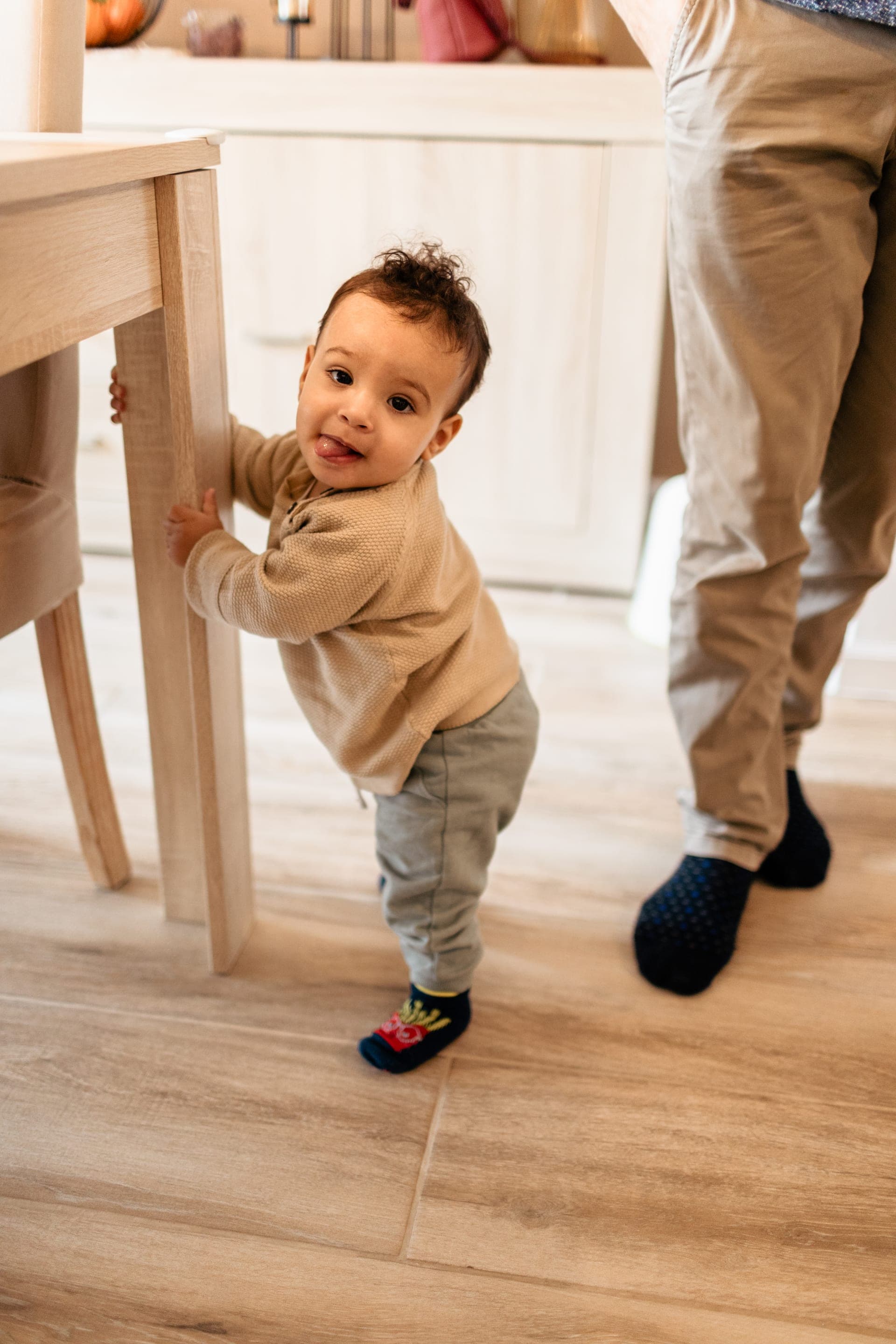 Bébé se tient debout contre une chaise premiers pas dans la cuisine — séance famille étapes