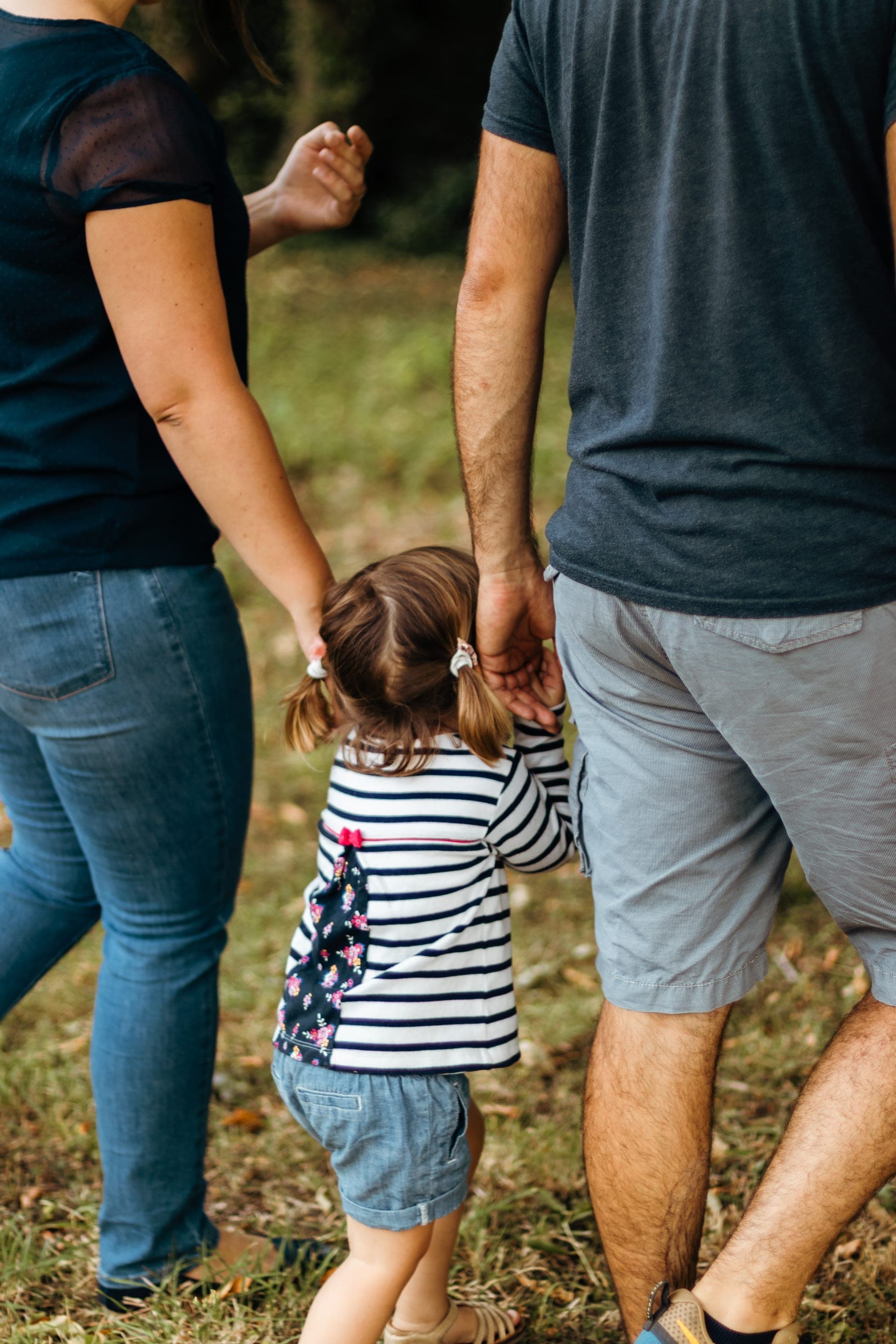Détail fille tient la main de ses parents sur un chemin — séance famille projet d'avenir