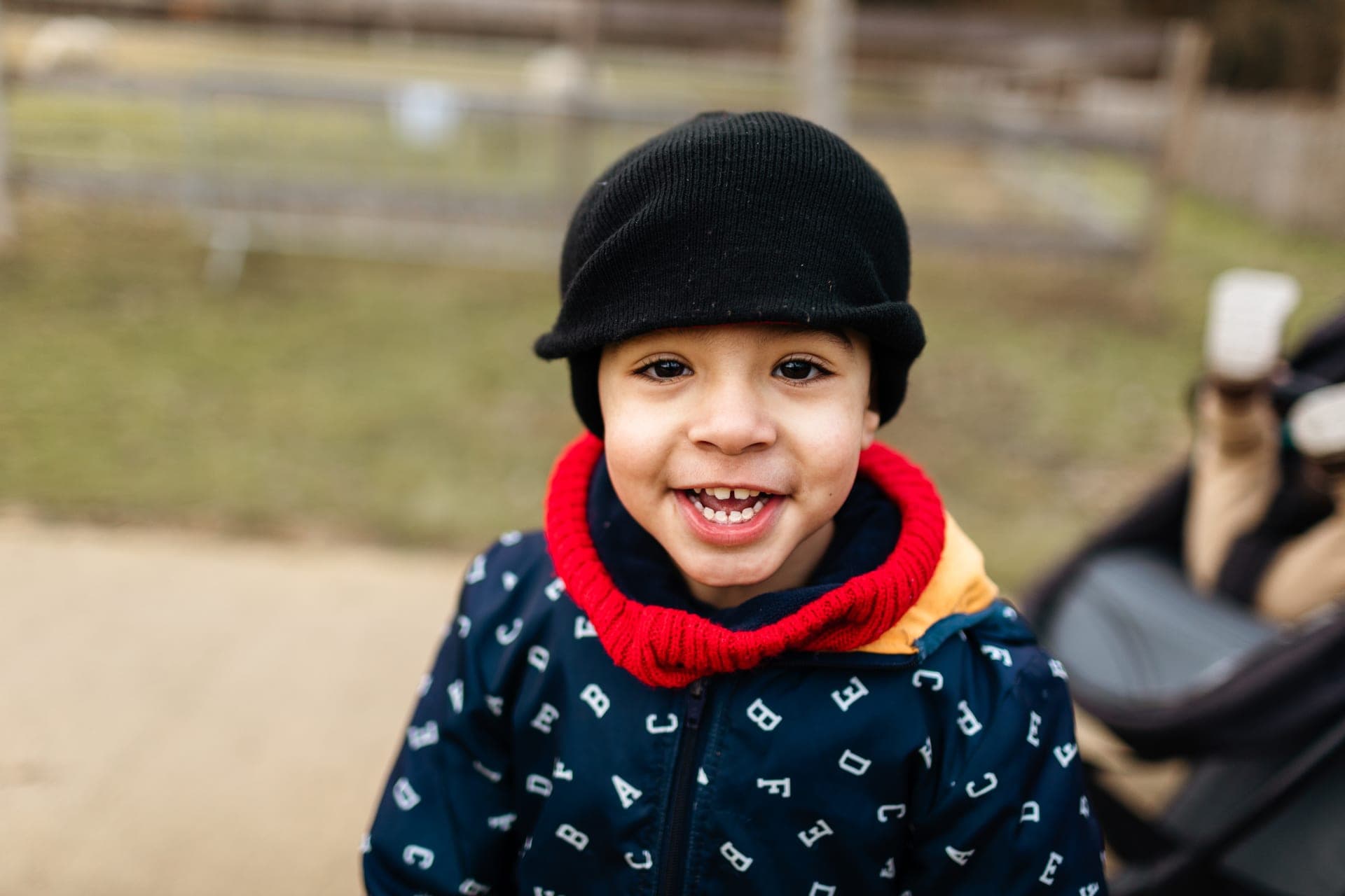 Enfant sur une trottinette sur un chemin de parc en hiver avec parent au loin — séance famille