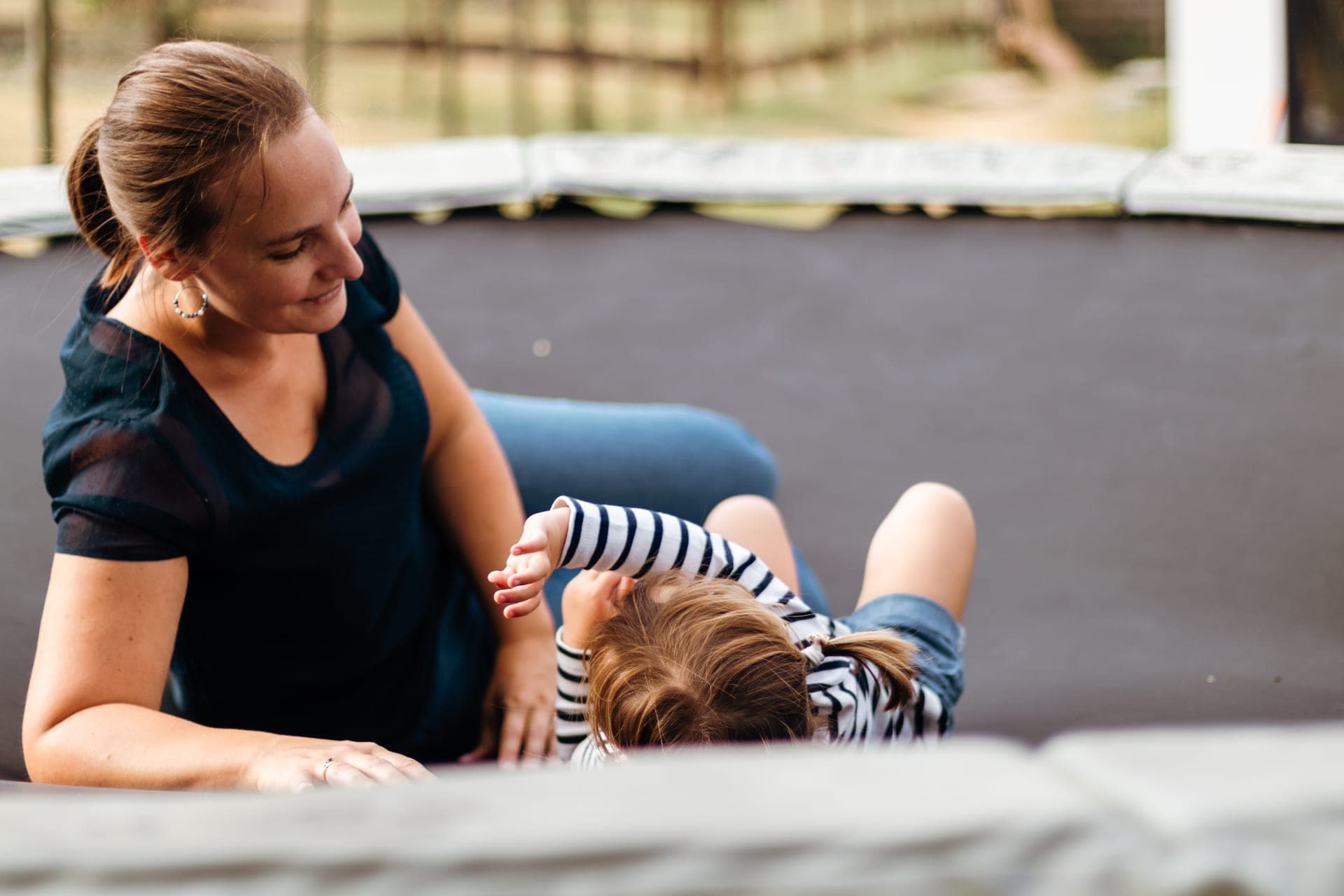 Maman et fille sur un trampoline dans le jardin complicité — séance famille extérieur