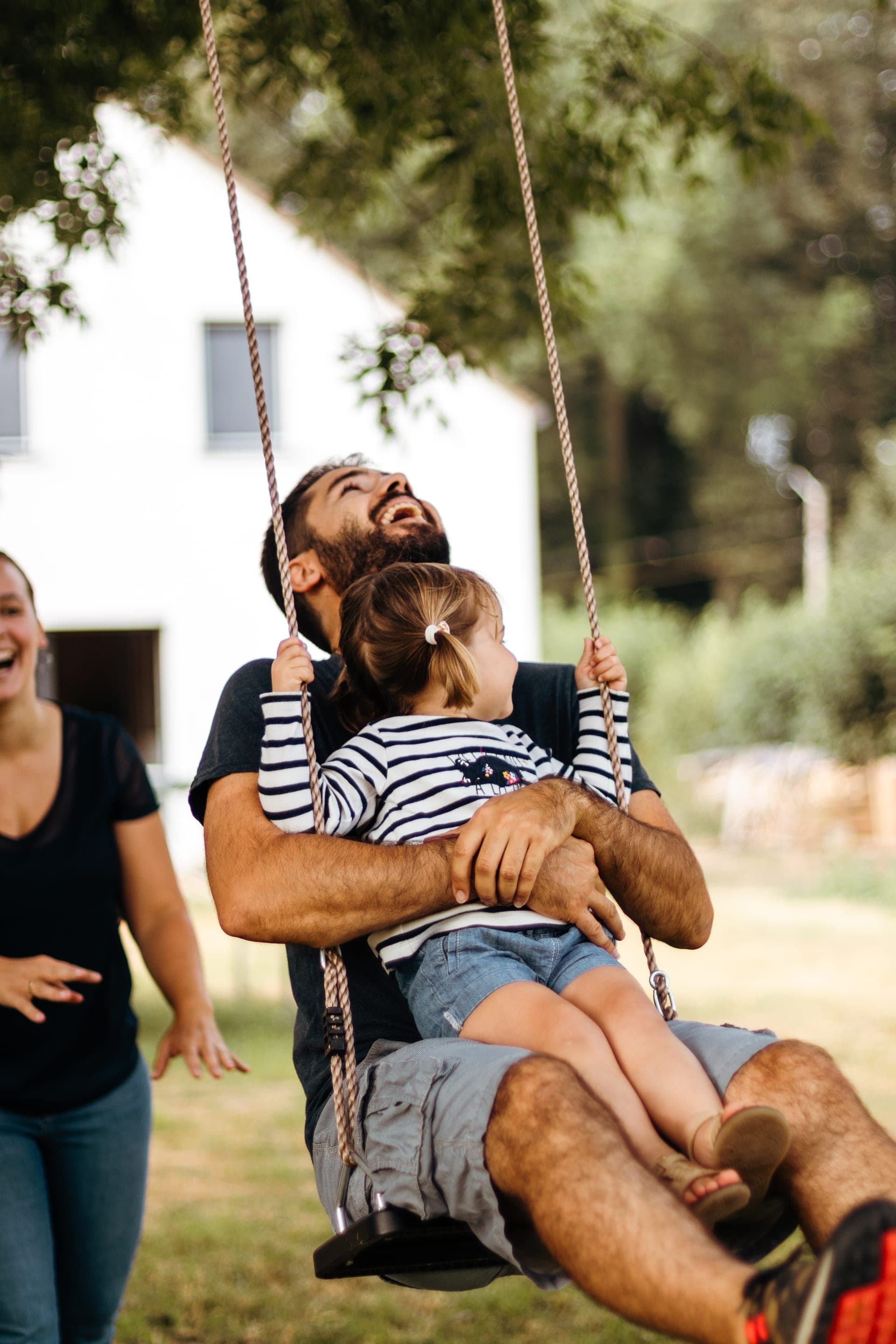 Papa et fille sur une balançoire éclat de rire dans le jardin — séance famille joie