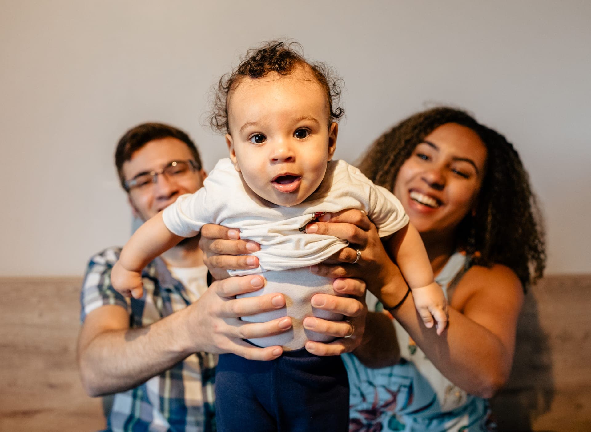 Parents soulèvent leur bébé éclat de rire joyeux — séance famille tendresse Aurore Clercq Photographie