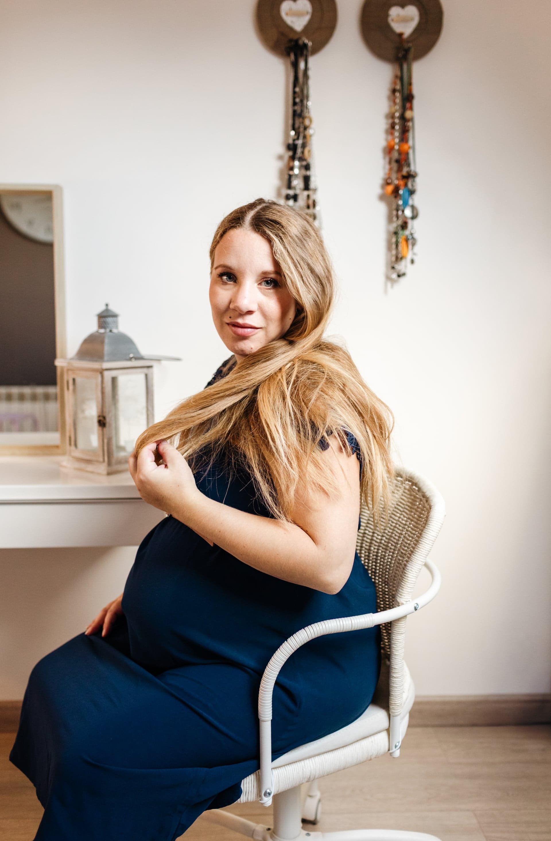 Future maman assise sur chaise en osier robe bleu marine regard caméra — portrait grossesse intimiste