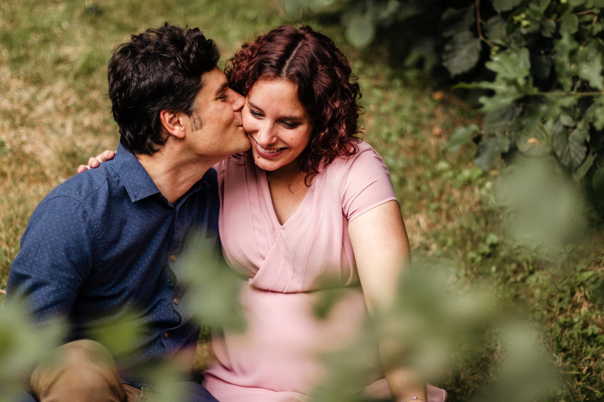 Couple enceinte baiser sur la tempe en pleine nature — complicité grossesse