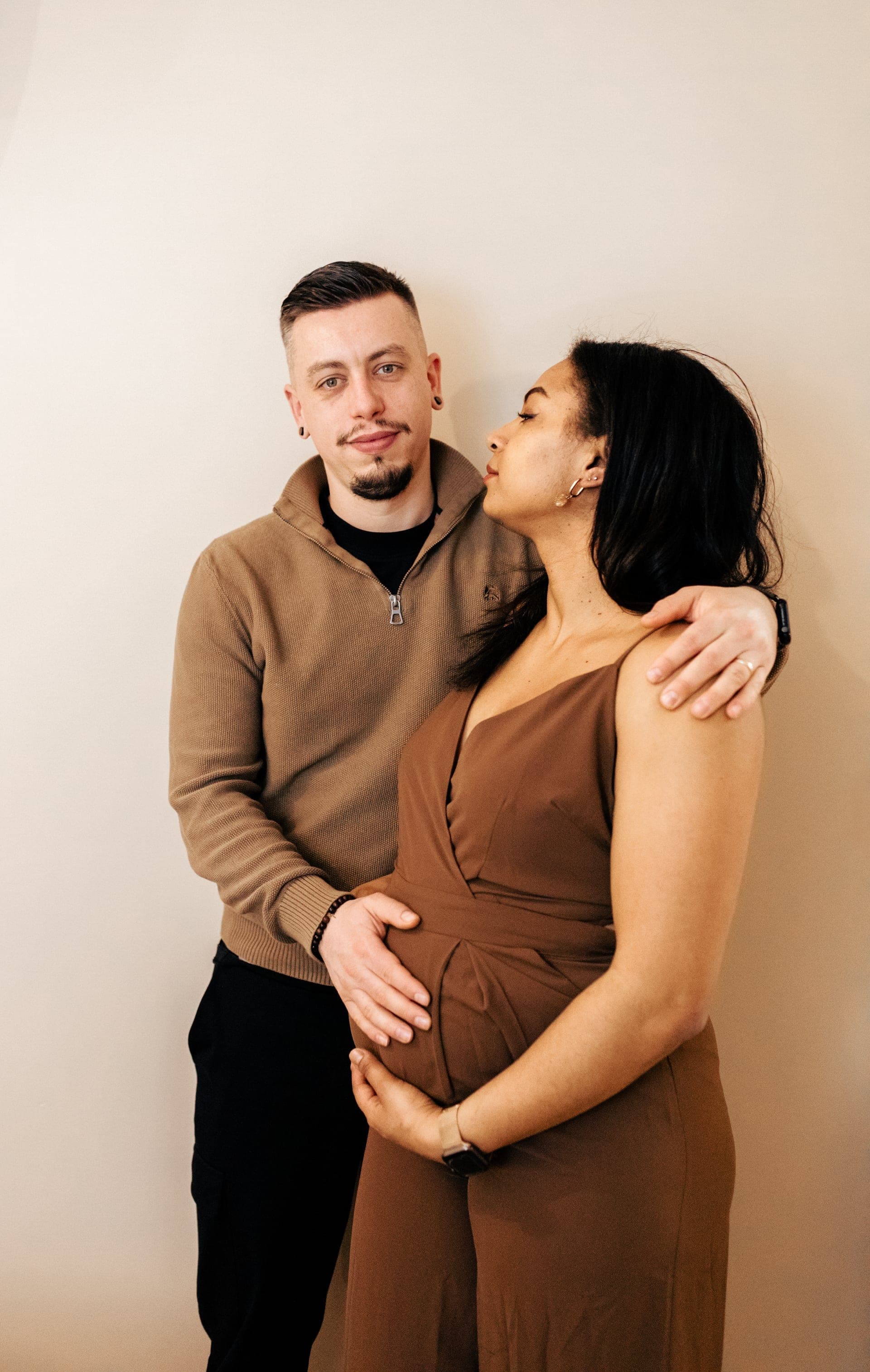 Couple enceinte enlacé en studio baiser sur la joue — séance grossesse tendresse