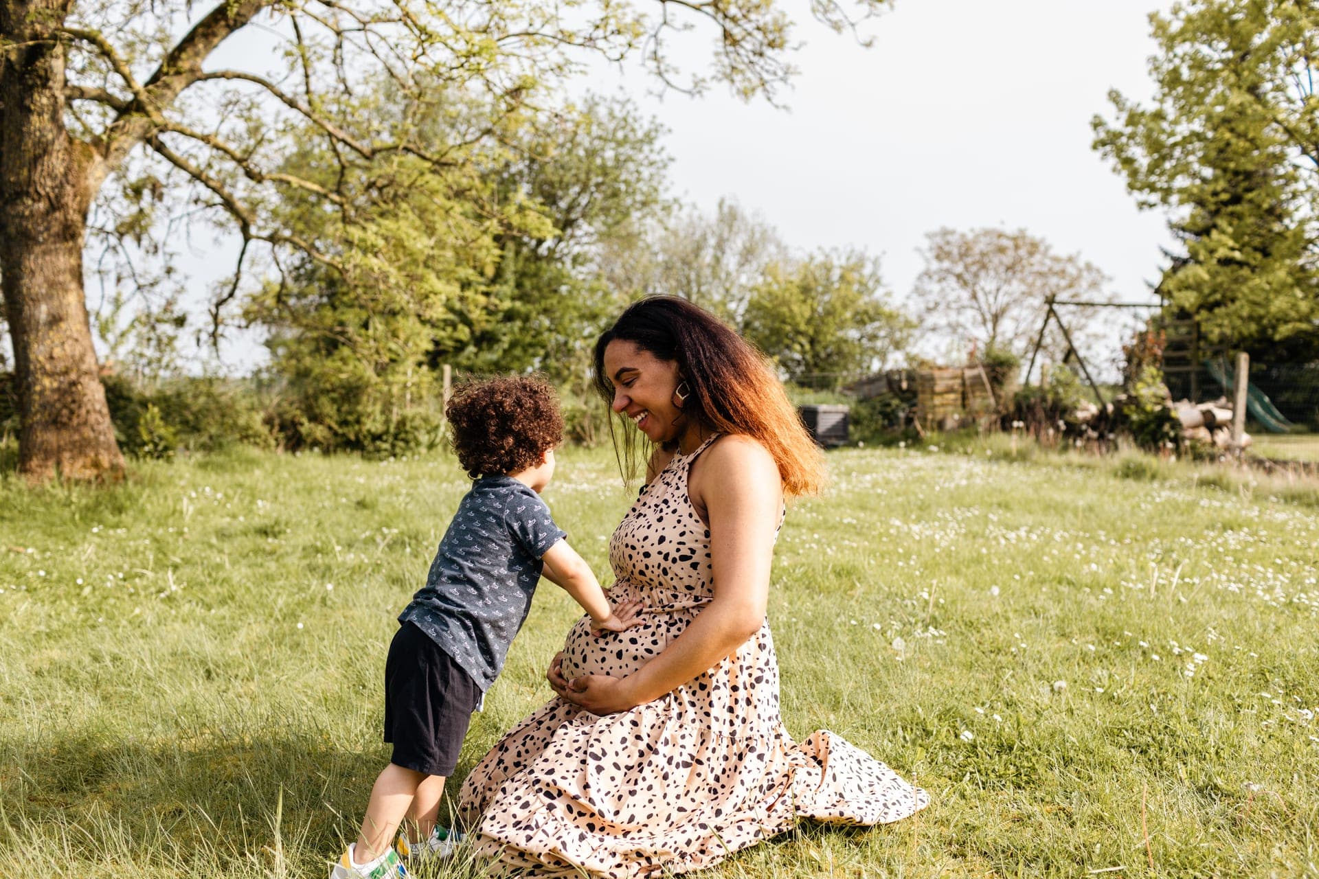 Enfant qui touche le ventre rond de sa maman — séance grossesse famille tendresse