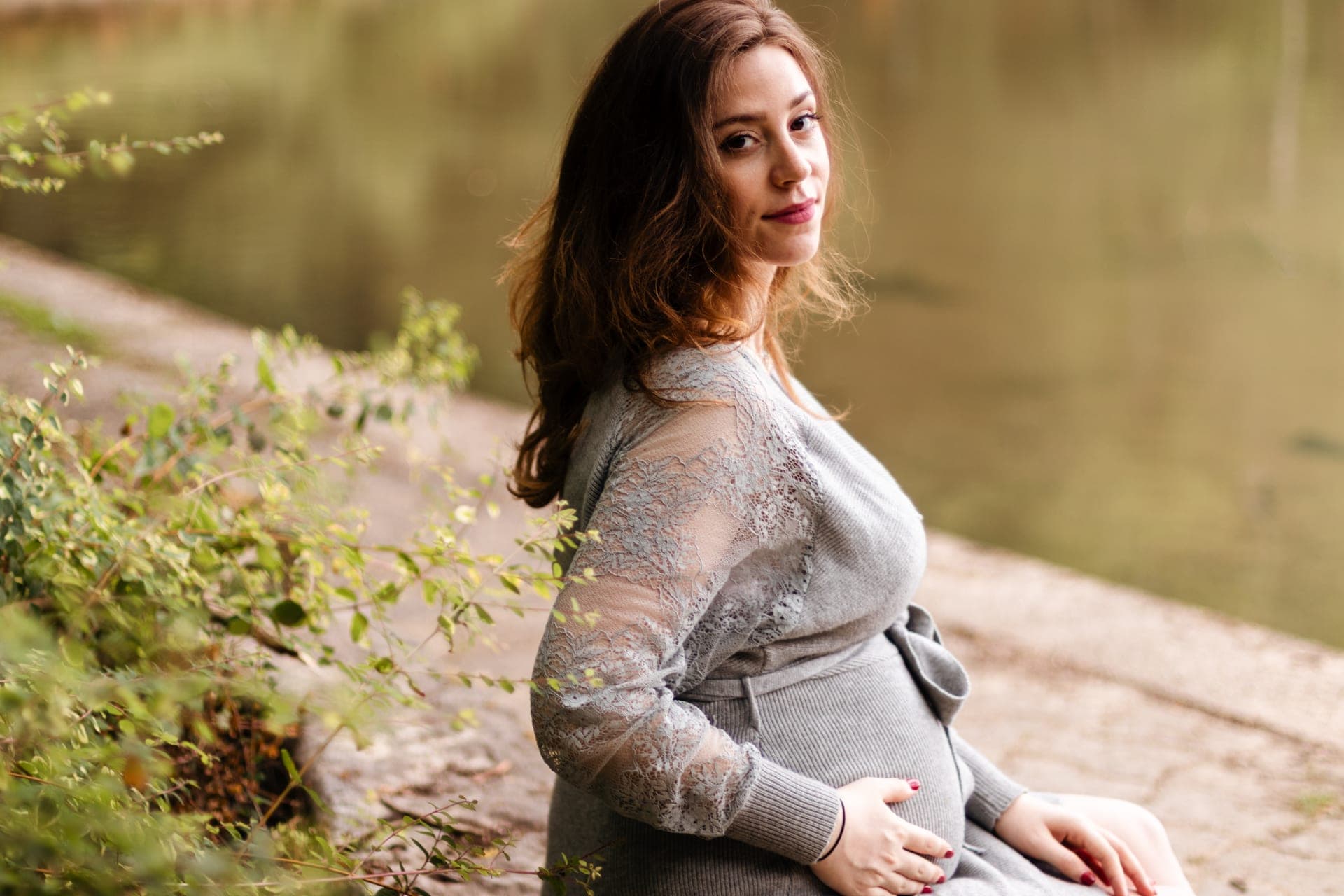 Future maman robe grise dentelle au bord d'un lac en automne — séance grossesse poétique