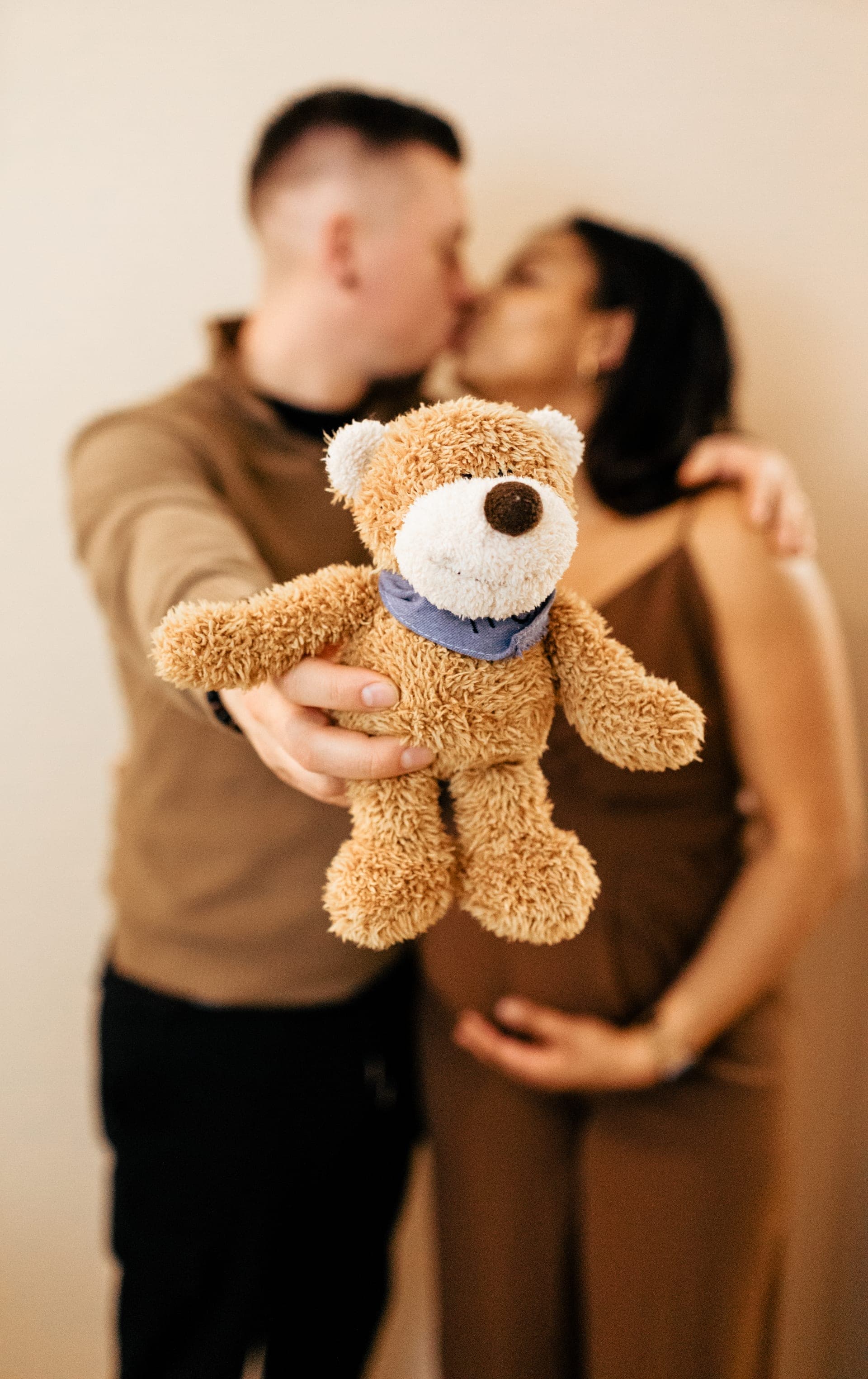 Couple enceinte baiser studio avec ourson en premier plan — grossesse créative