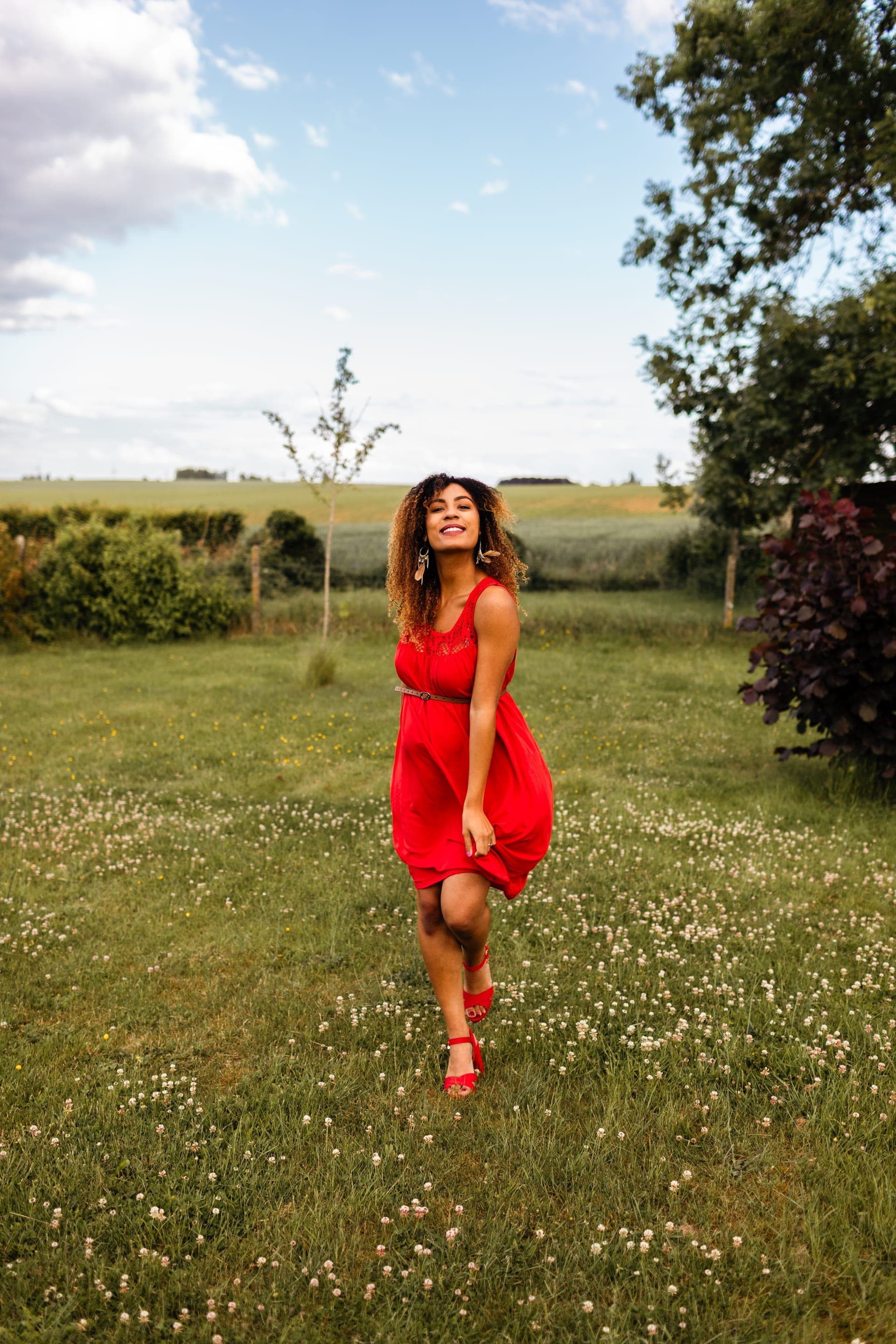 Future maman dans un champ fleuri robe rouge — séance grossesse extérieur été