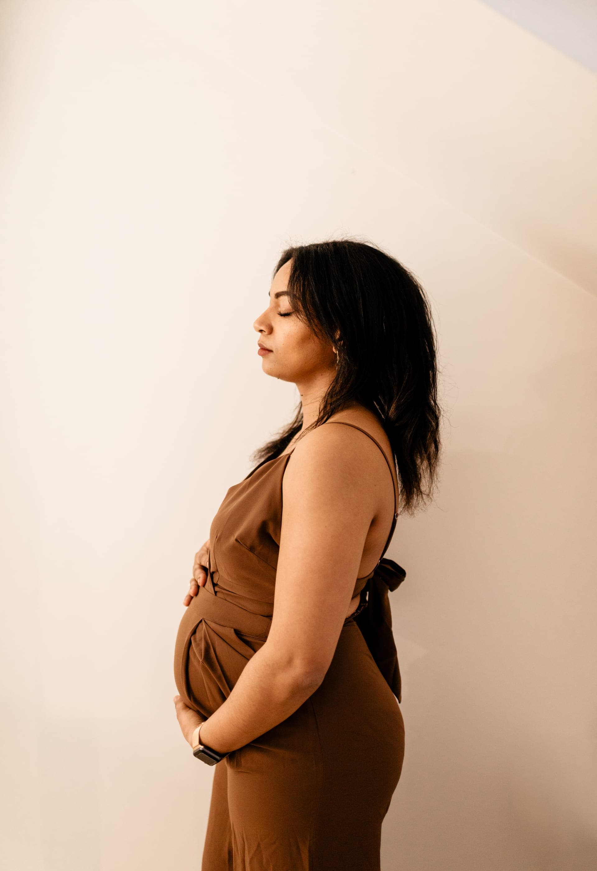 Portrait profil studio d'une femme enceinte en robe caramel — sérénité grossesse