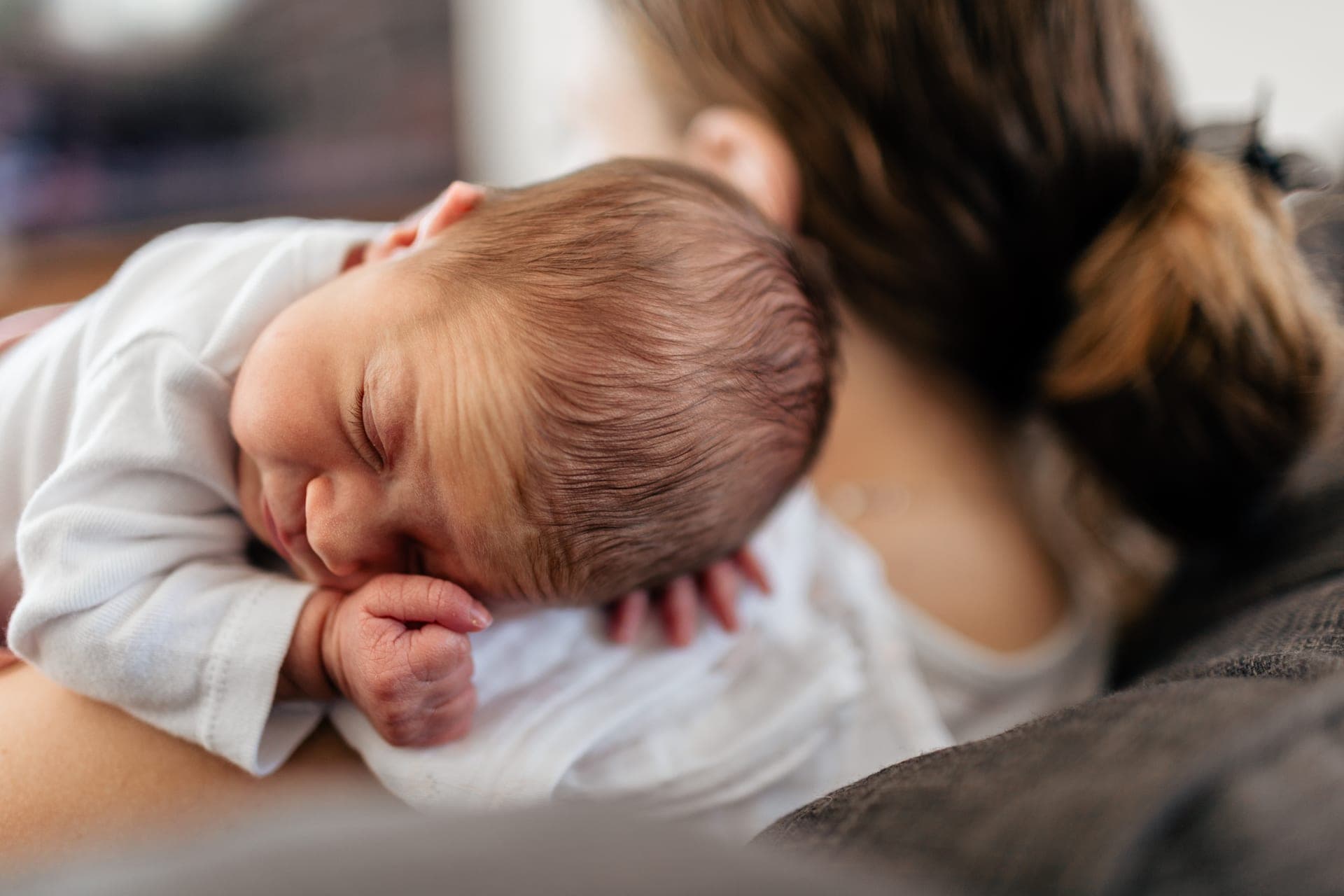 Bébé endormi sur l'épaule de sa maman peau à peau — détail séance naissance
