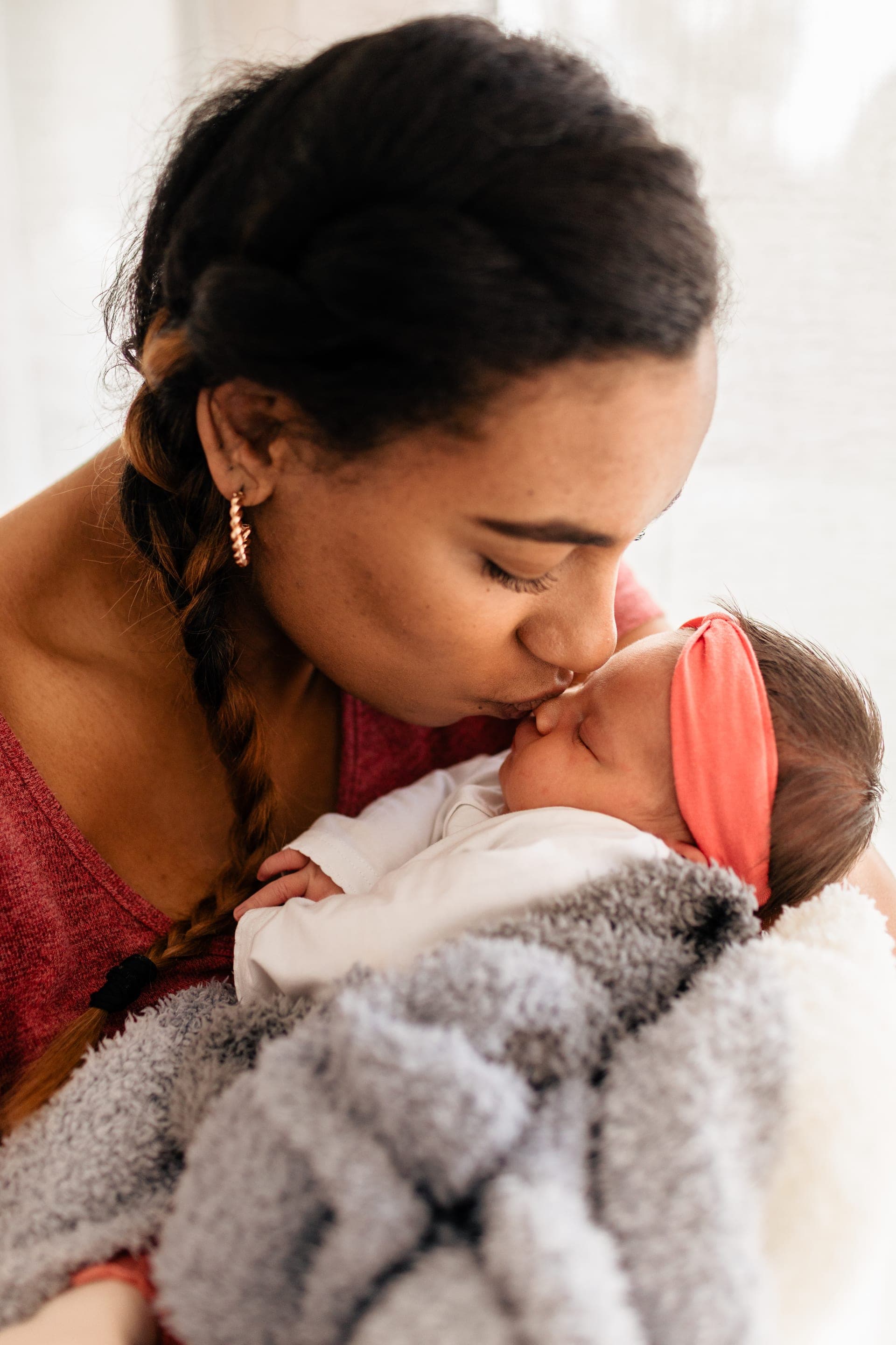 Maman embrasse le front de son nouveau-né bandeau rose — tendresse séance naissance