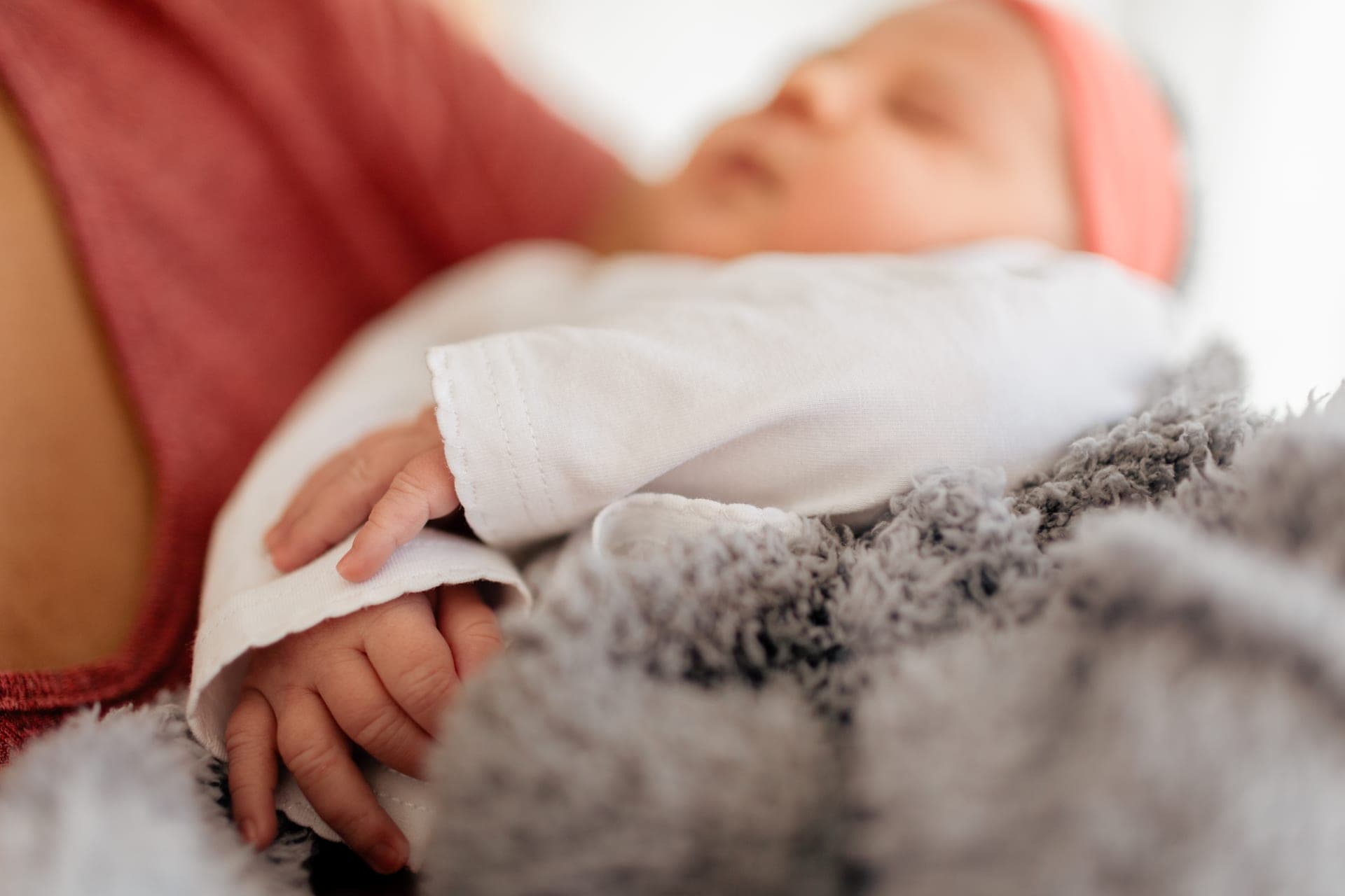 Maman tient son nouveau-né bandeau rose dans une lumière douce — séance naissance