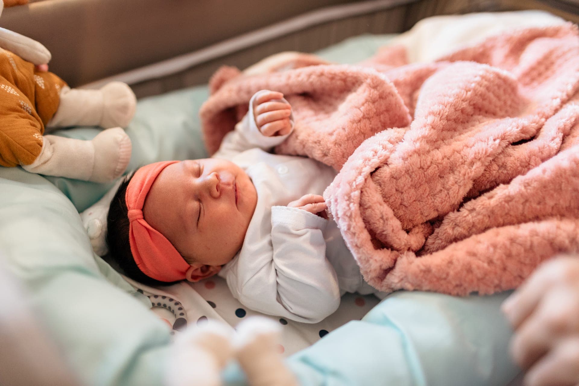 Nouveau-né endormi dans son couffin avec couverture rose — séance naissance lifestyle