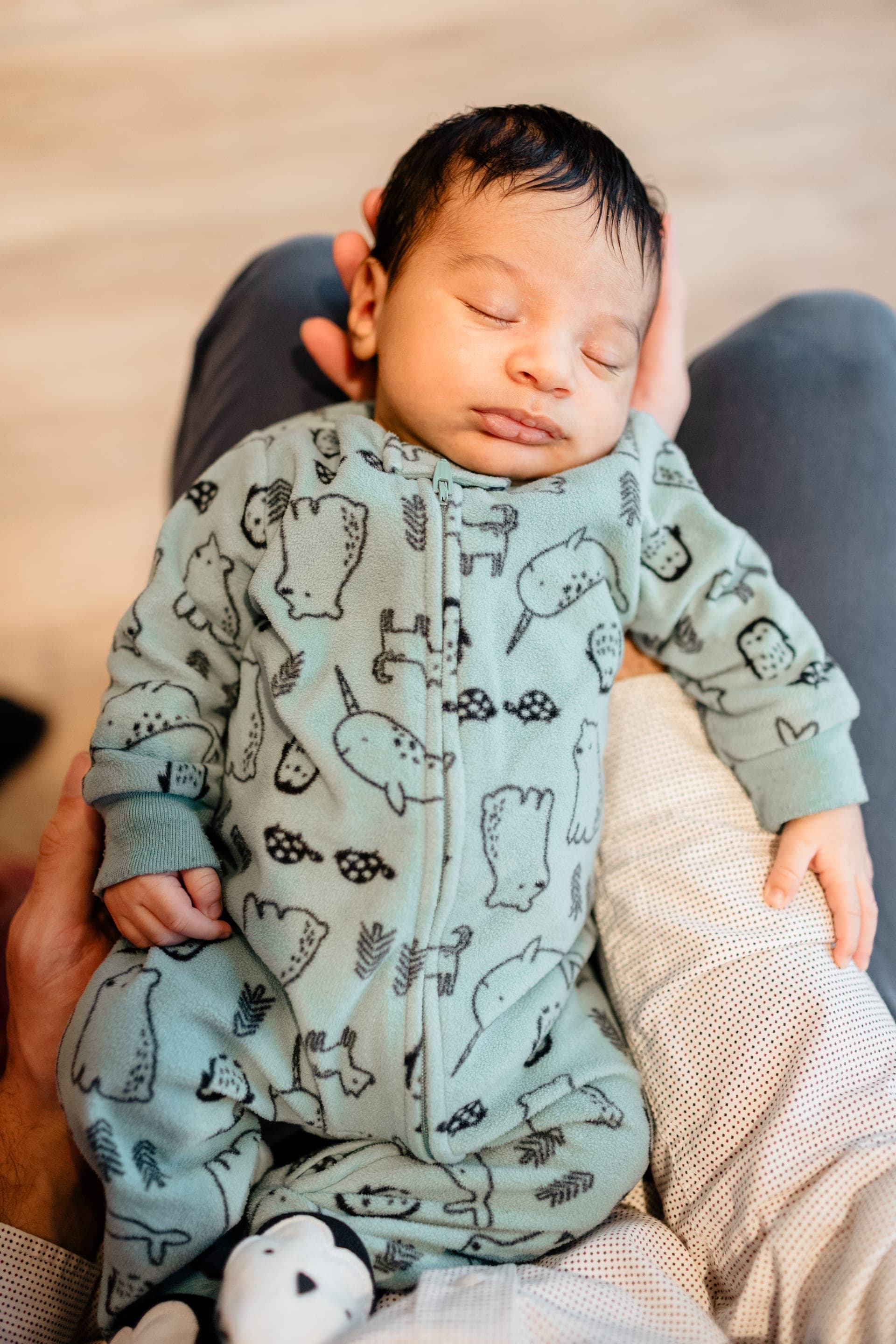 Nouveau-né endormi pyjama bleu aux motifs animaux — séance naissance douceur