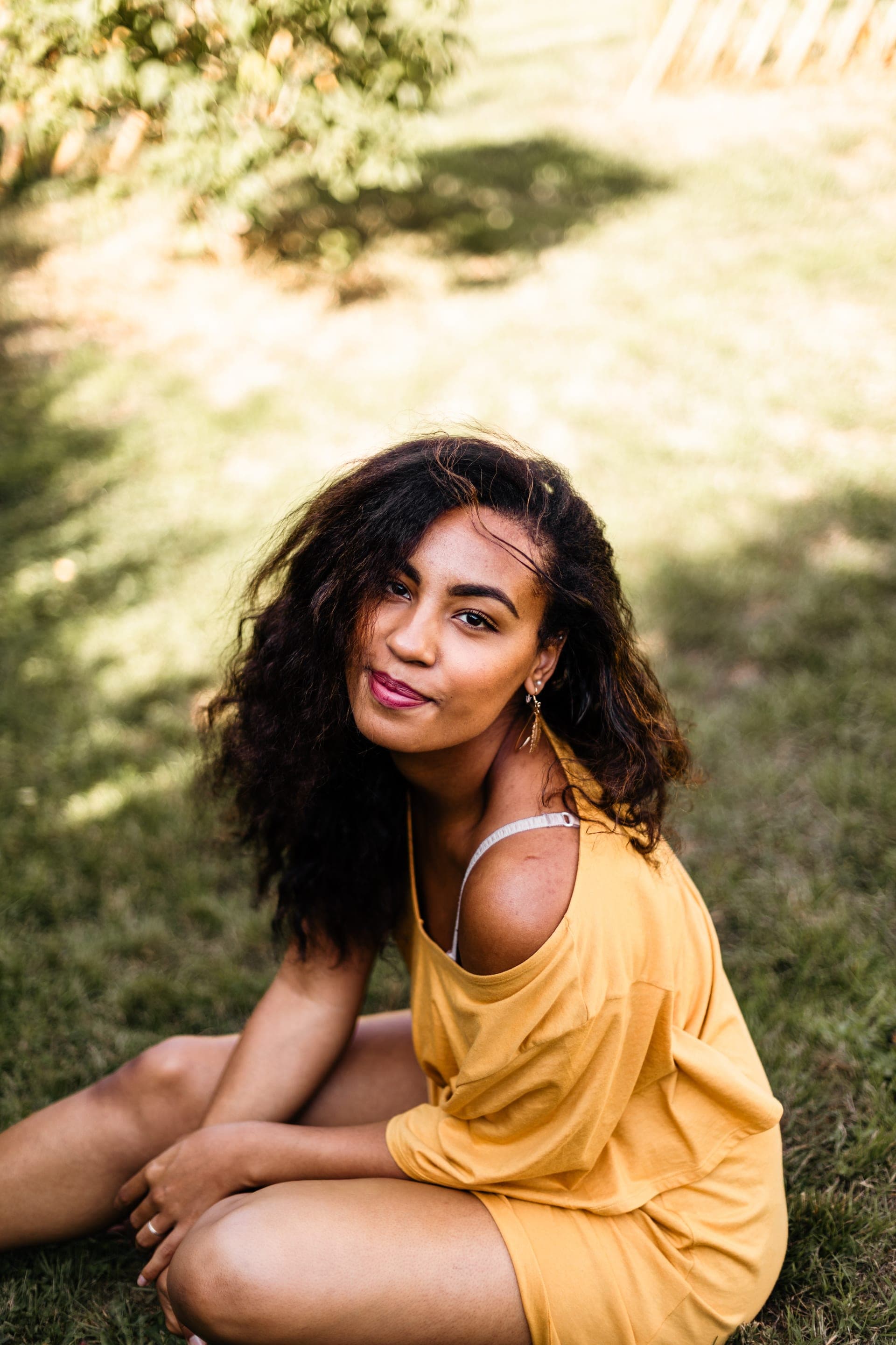 Portrait femme assise dans l'herbe top jaune sourire doux lumière d'été — séance portrait douceur Brabant Wallon