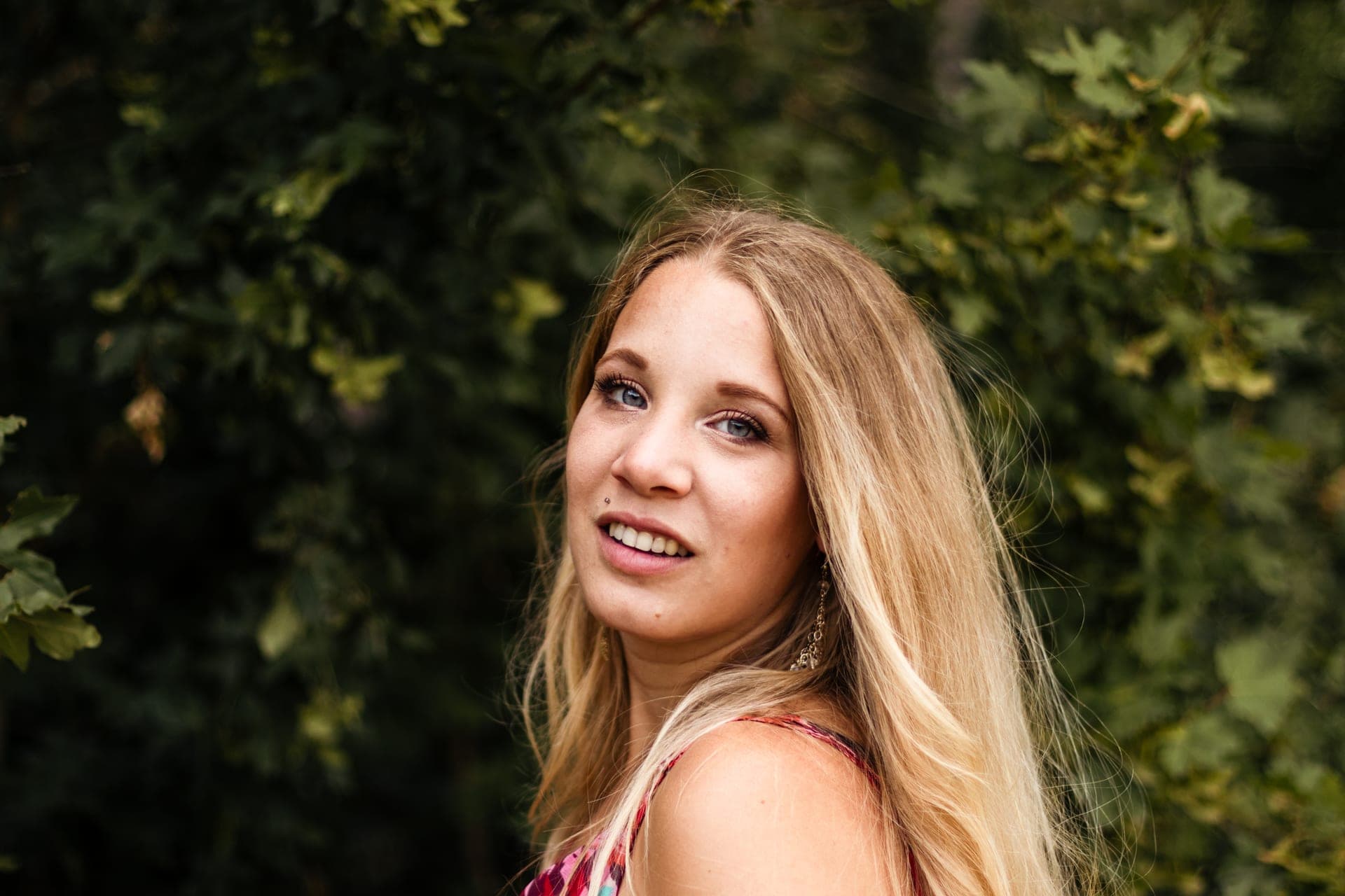 Portrait femme blonde sourire doux devant feuillage vert en été — séance portrait douceur
