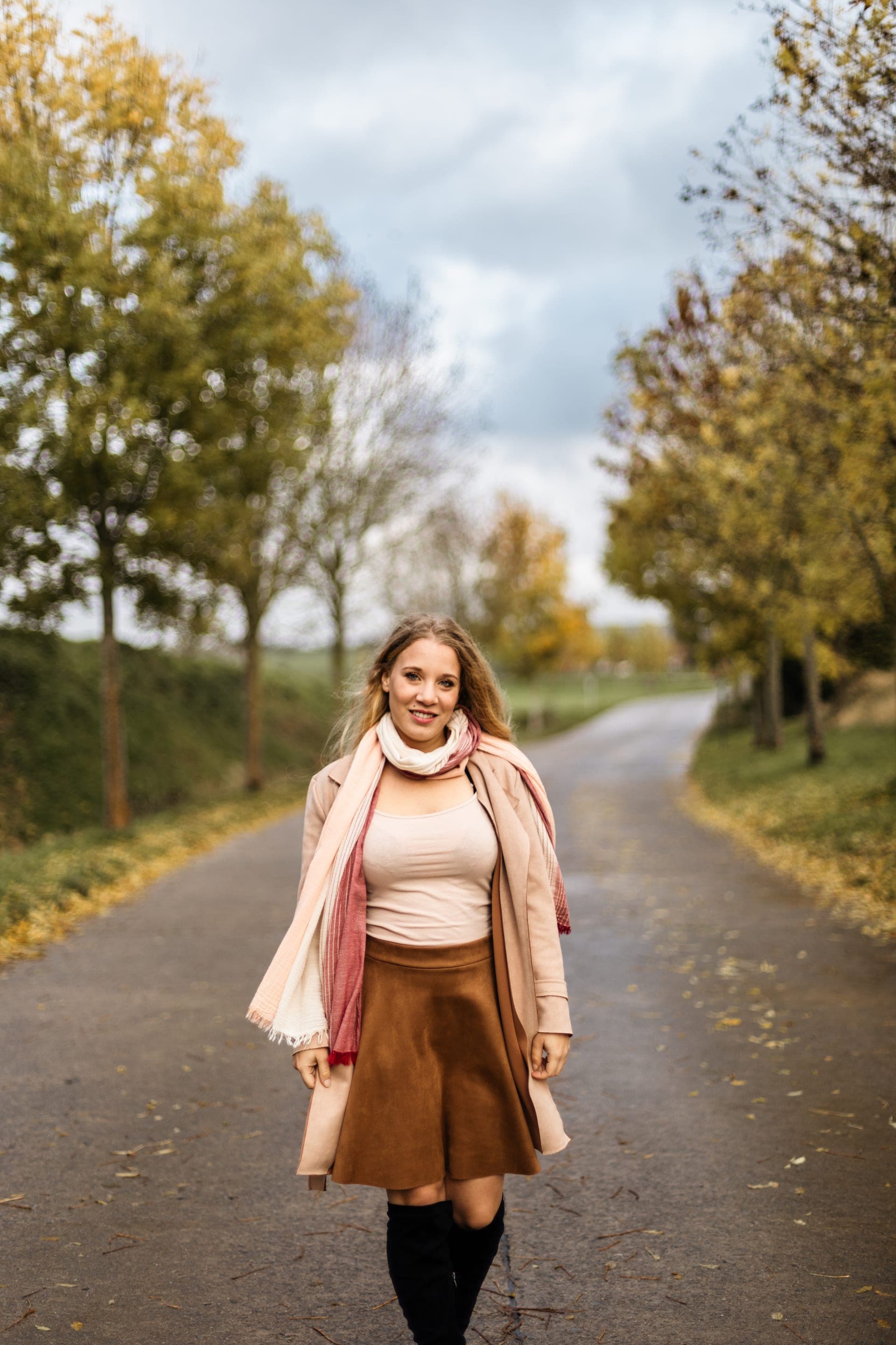 Portrait femme sur un chemin bordé d'arbres en automne manteau rose — séance portrait nature