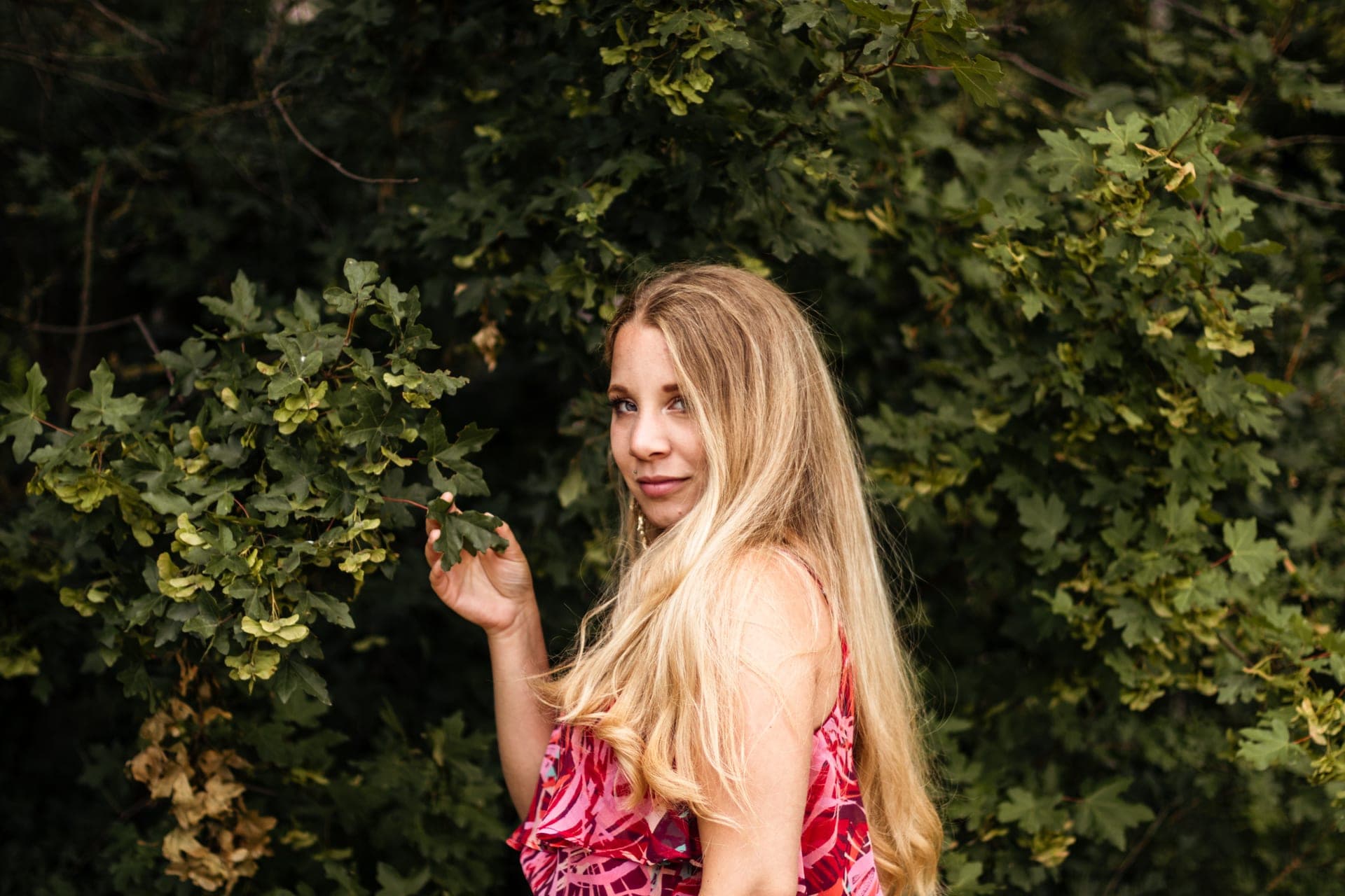 Portrait femme profil tient une feuille verte dans la main robe rouge — détail séance portrait