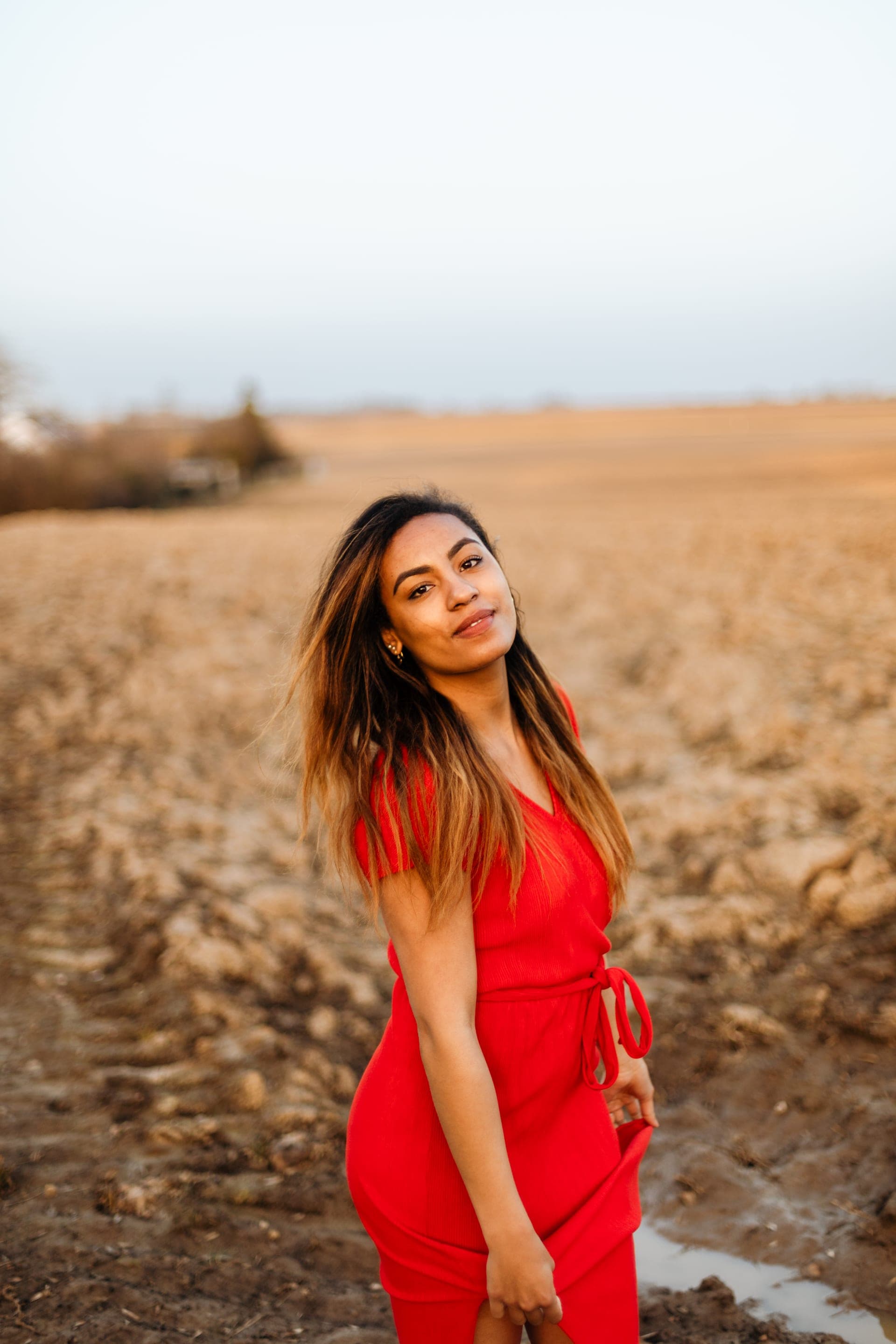 Portrait femme en robe rouge dans un champ labouré aux tons ocre — séance portrait Brabant Wallon