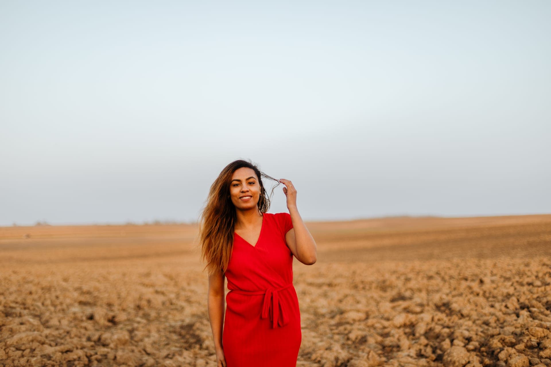 Portrait femme en robe rouge dans un champ rire doux à l'horizon — Aurore Clercq Photographie Brabant Wallon