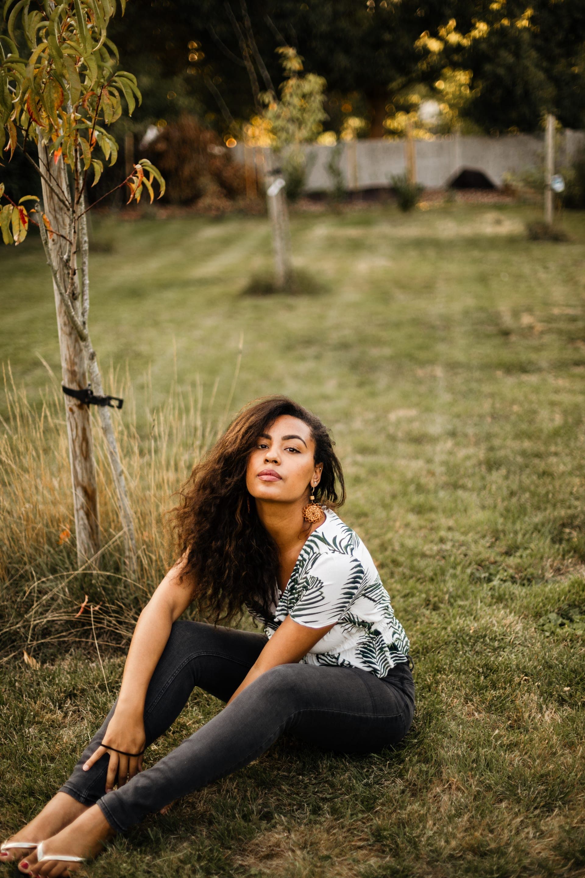 Portrait femme top fougères assise dans l'herbe près d'un jeune arbre — séance portrait nature lifestyle
