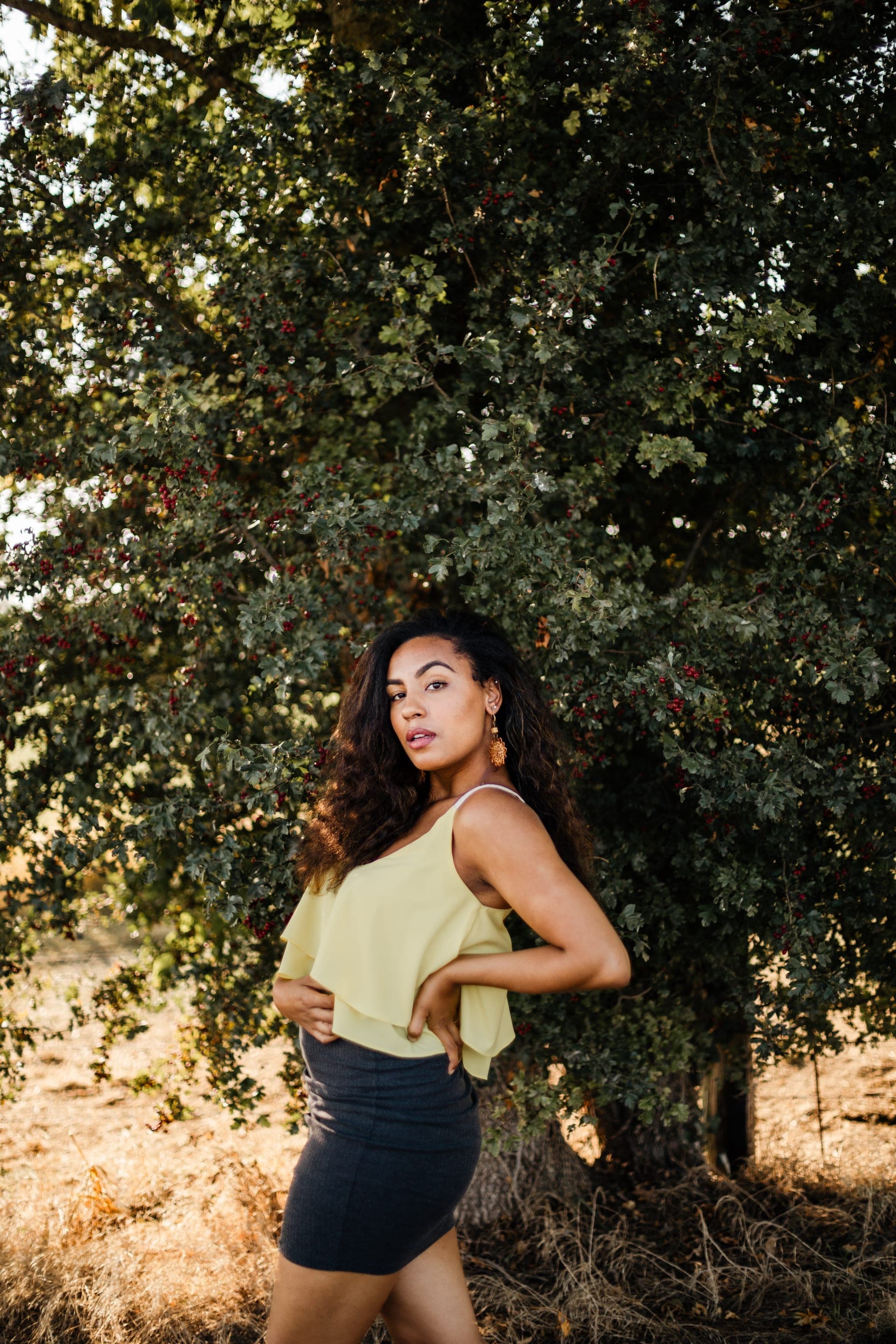 Portrait femme top jaune jupe noire profil devant arbre feuillage baies rouges — séance portrait nature été