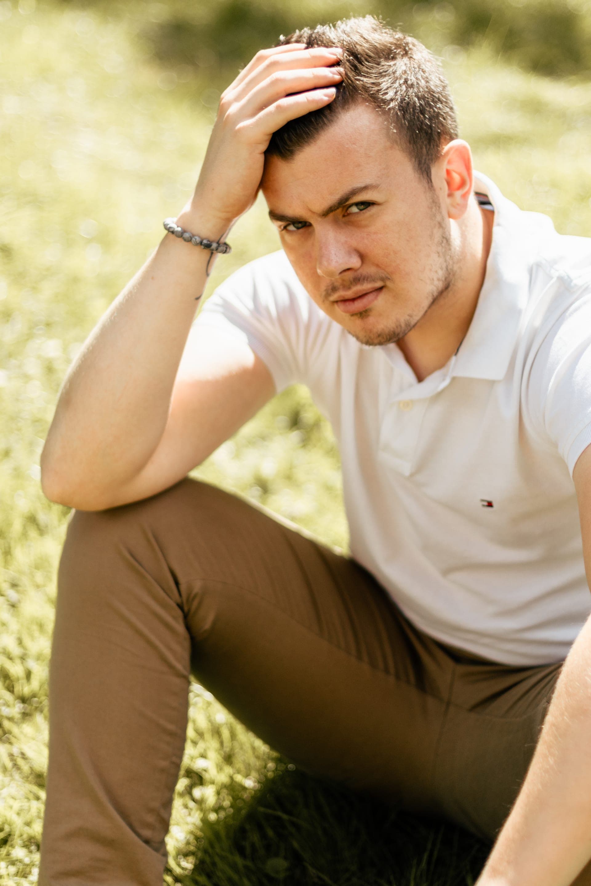 Portrait homme assis dans l'herbe main dans les cheveux regard intense — séance portrait naturel