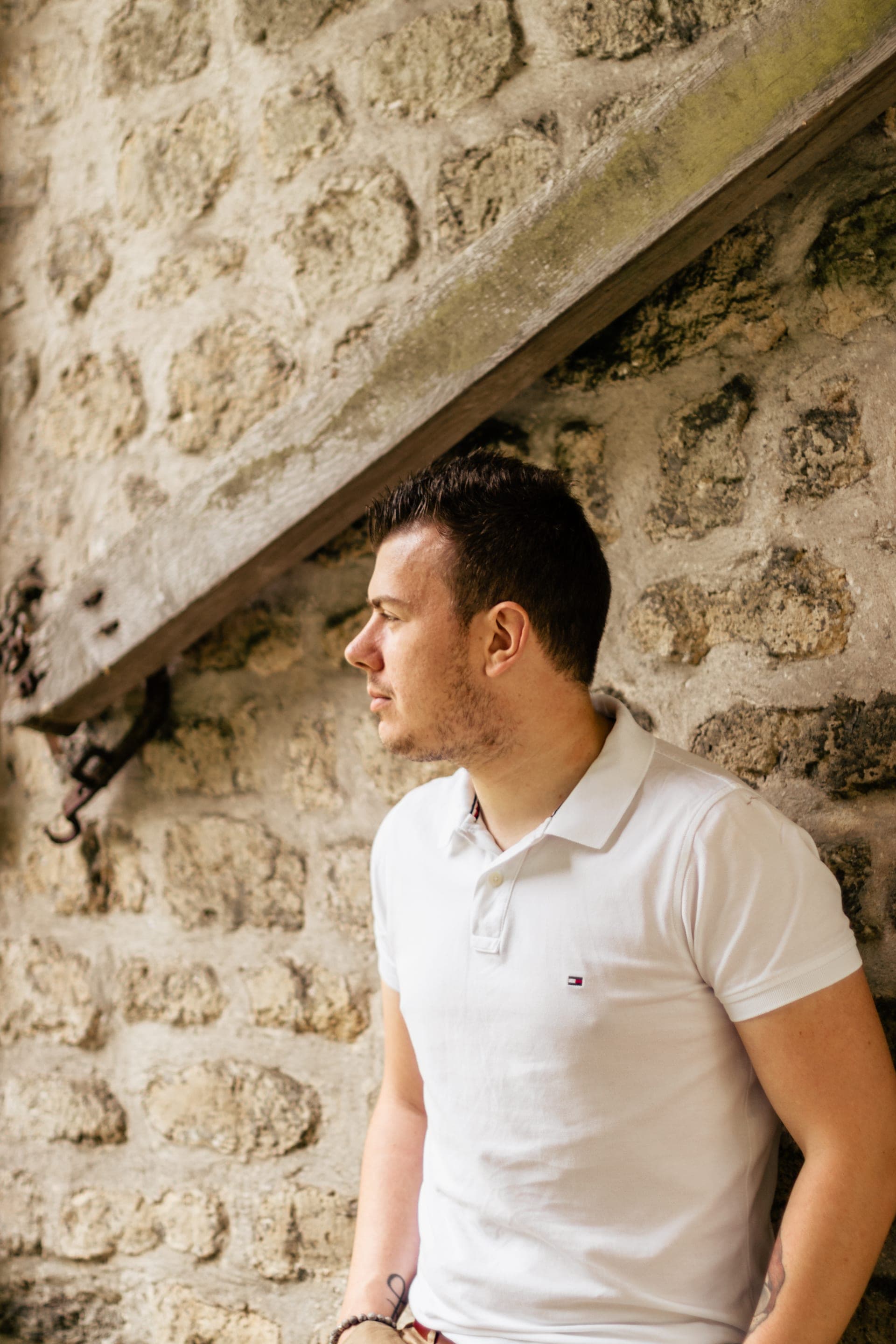 Portrait homme de profil devant un mur en pierre t-shirt blanc — séance portrait masculin élégance